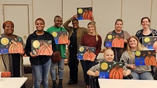 Teen group holding pumpkin paintings