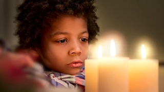 Boy looking at lit candles