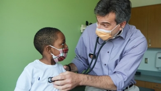 Doctor listening to young boy's heartbeat