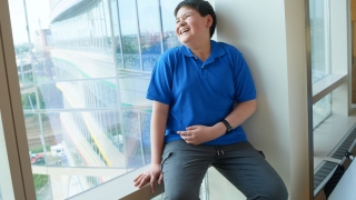 Young boy cancer patient sitting in hospital window laughing