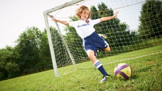 Tween girl playing soccer in front of net