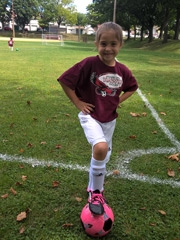 Elise smiling on soccer field standing with ball