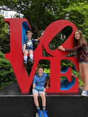 family standing smiling on LOVE statue
