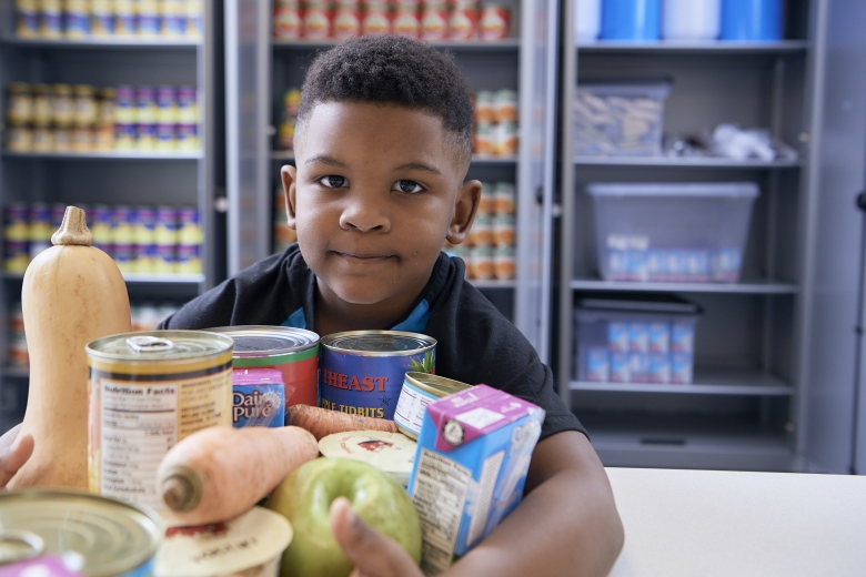 boy holding canned goods at food pharmacy