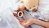 Patient's hand holding pills and bottle Parent's hand hold pills and bottle