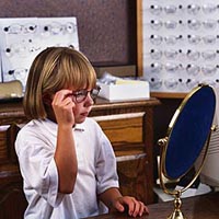 Picture of a young girl trying on a pair of eyeglasses