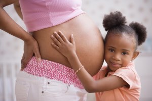 Close up video of young girl hugging and pressing her ear to her mother's pregnant belly