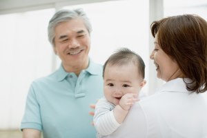 Grandmother holds baby while grandfather looks on.