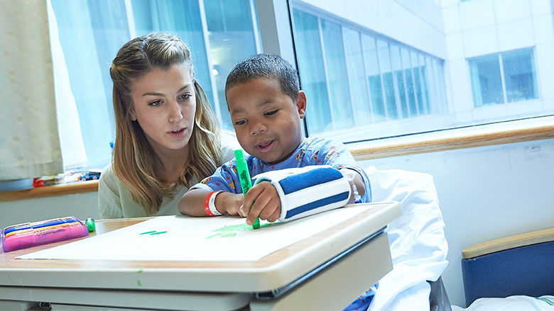 Aid with child in hospital room, color together