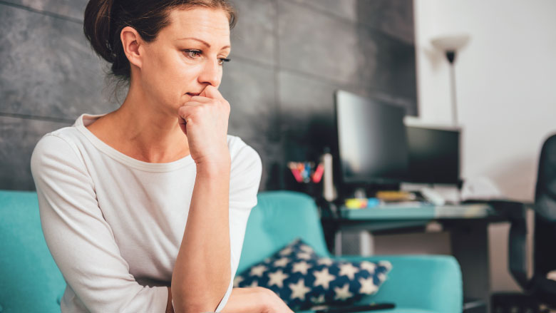 Sad woman sitting on a sofa in the living room