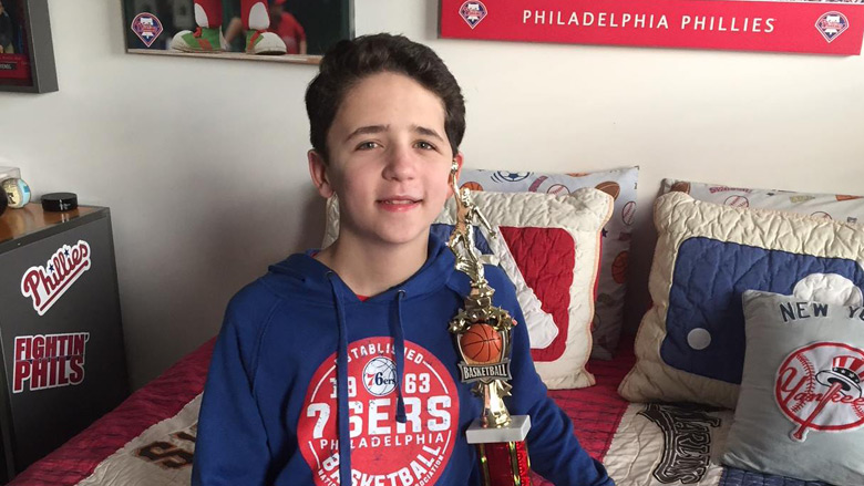 Chase sitting in his room with a basketball trophy