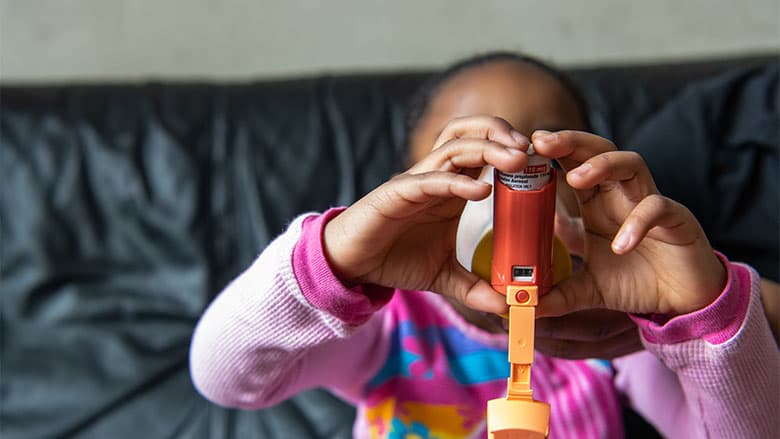 Child using inhaler with help of adult Child using inhaler with help of adult