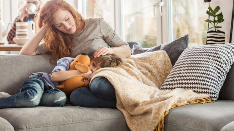 Mother laying on couch comforting sick child