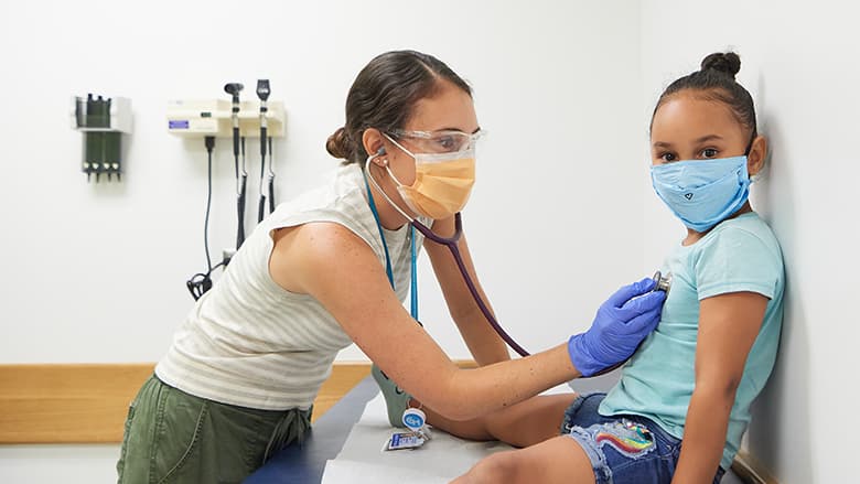 Doctor with mask checking patient heartbeat