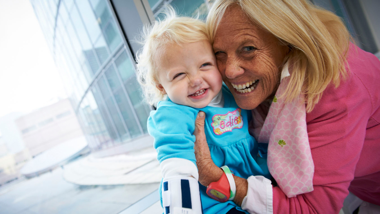 Young boy hugging an adult leg in a hospital room