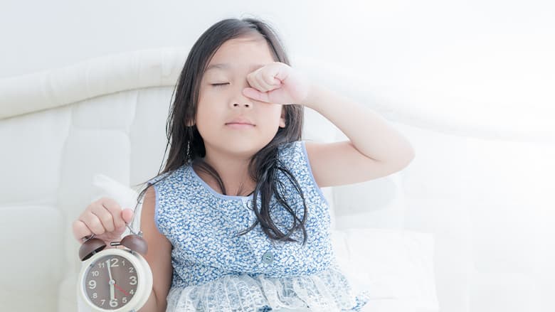 Young girl in bed with an alarm clock