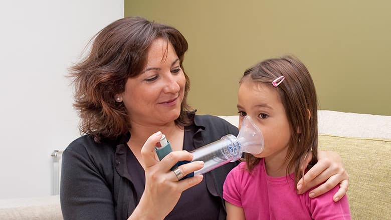 Mother helping daughter with inhaler