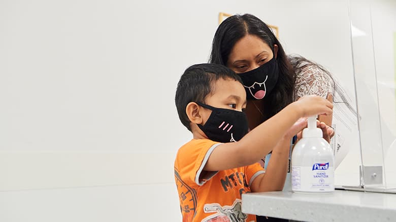 Adult helping child use hand sanitizer Adult helping child use hand sanitizer