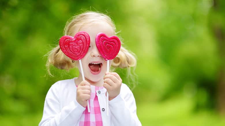 Girl holding two lollipops in front of her eyes