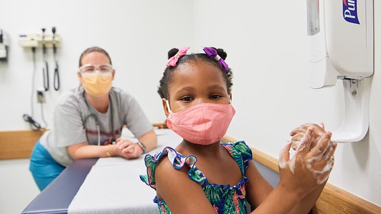 Young girl wearing mask in doctor's office with nurse