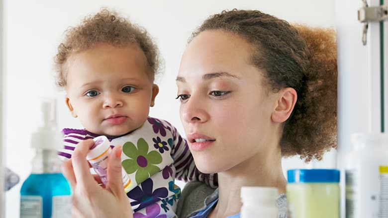 Mother holding son near open medicine cabinet