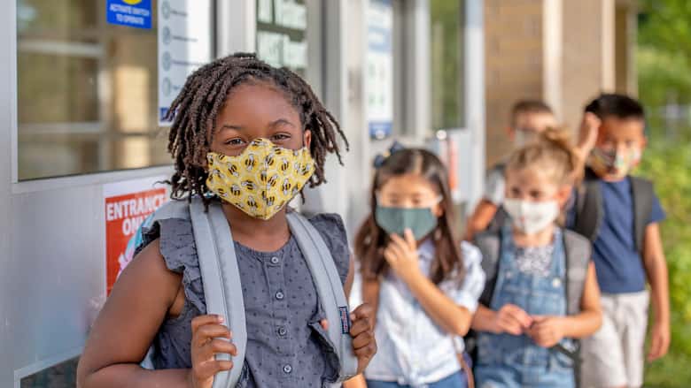 Children gathering outside of school wearing masks