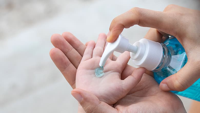 Parent's hands using sanitizer on child's hands