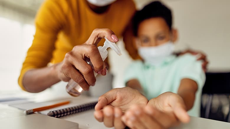 Mother using pump sanitizer on son's hands