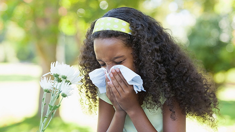 Young girl sneezing next to flowers