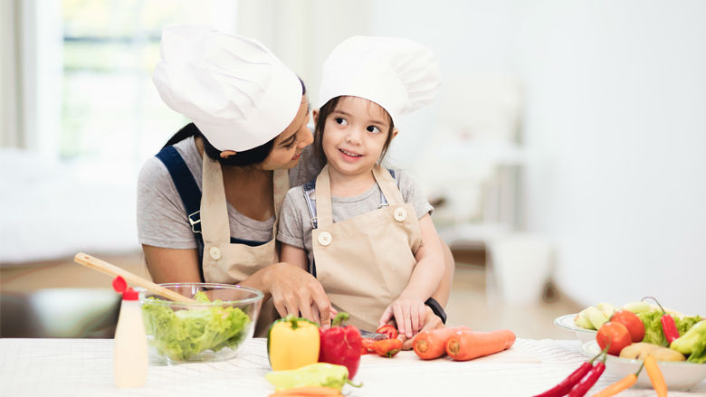 Mom cutting vegetables with daughter