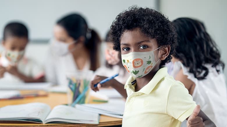 Child wearing protective mask in classroom setting Child wearing protective mask in classroom setting