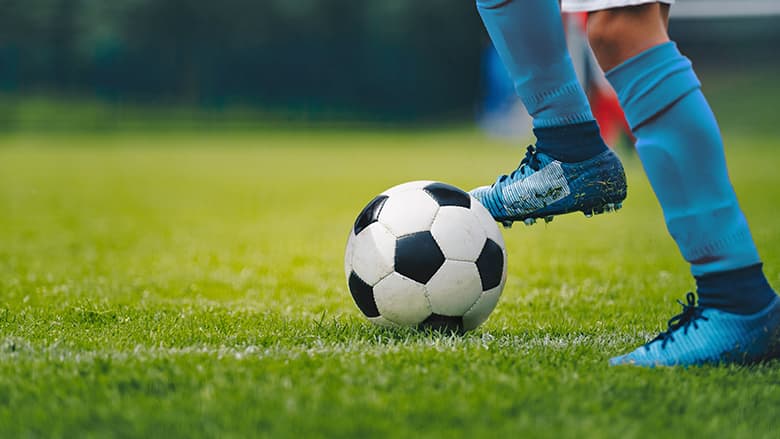 Closeup of soccer player's cleats and soccer ball