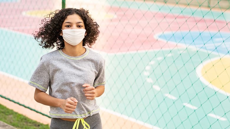 Teen athlete jogging outside wearing a protective mask Teen athlete jogging outside wearing a protective mask