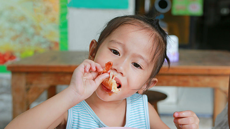 Young girl eating shrimp