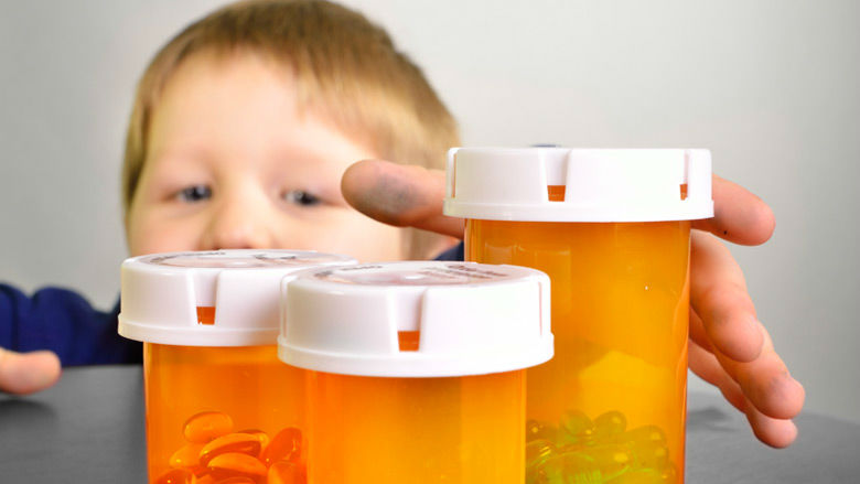 young boy reaching for pill bottles