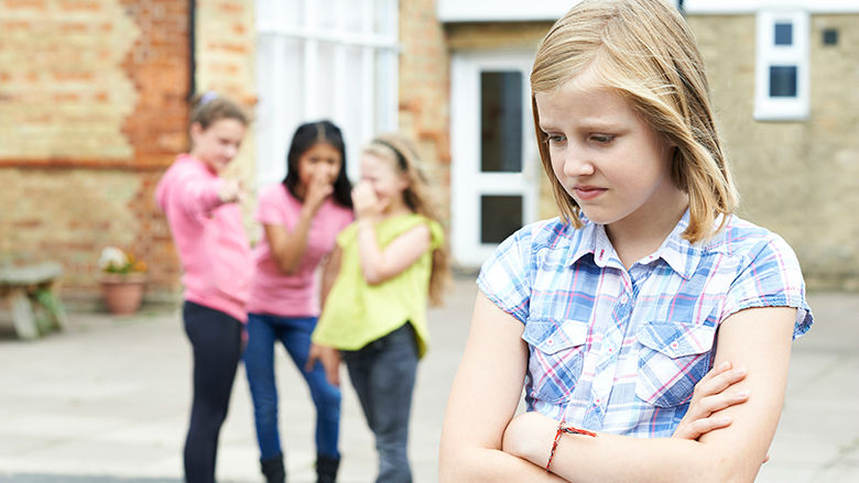 Sad looking girl with other girls laughing Sad looking girl with other girls laughing