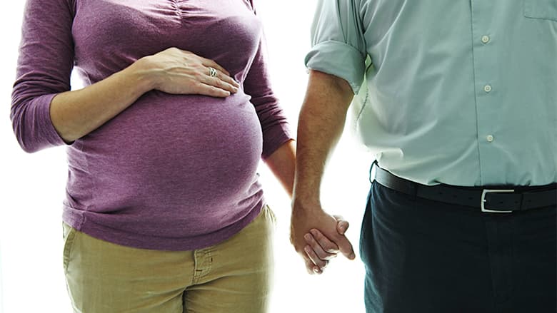 Person holding hand of pregnant mother