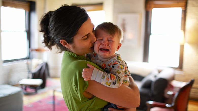 Cranky child being held by his mom