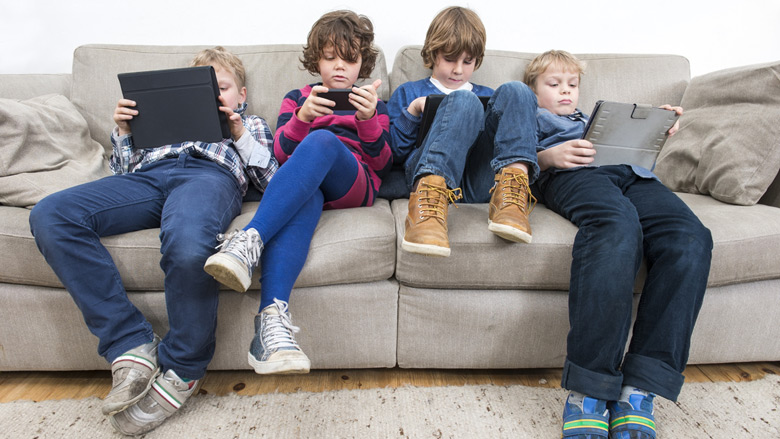 Kids on couch playing with gadgets being inactive