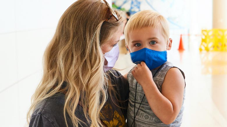 Mom holding son, both in masks