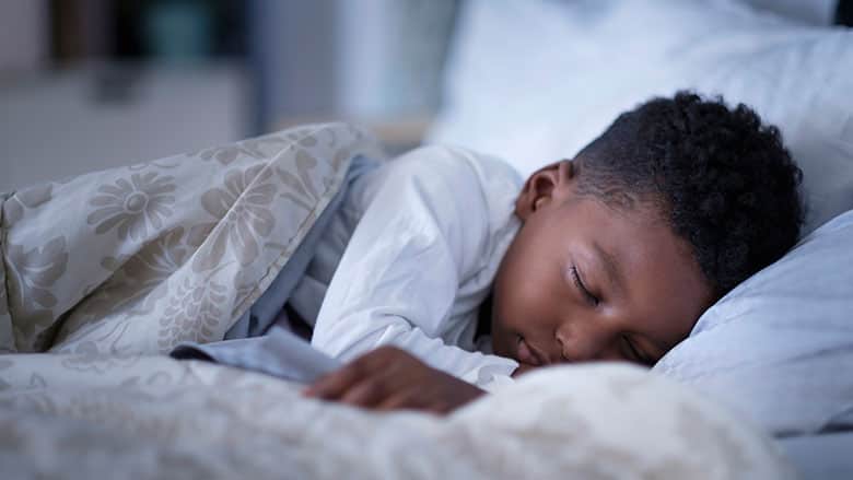 Child tucked into bed with white covers Child tucked into bed with white covers