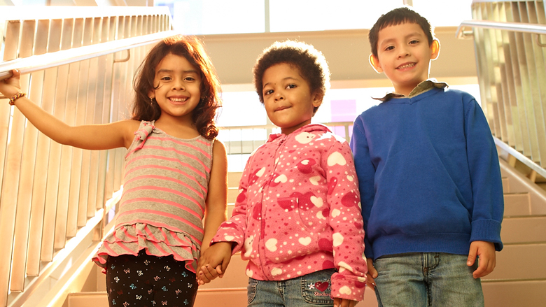 three children holding hands and smiling