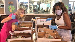 Two employees packing produce boxes Two employees packing produce boxes