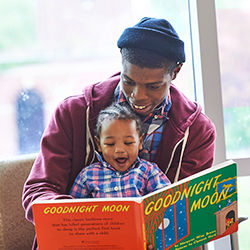 Mom holding daughter with book in exam room