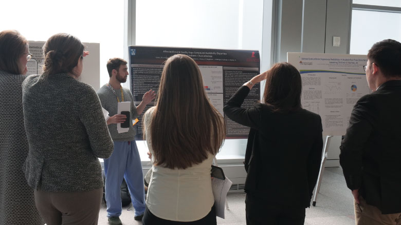 Conference attendees listening to a poster presentation