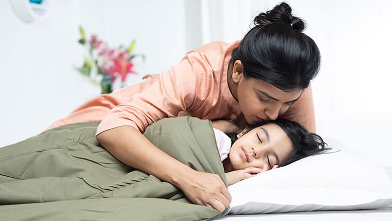 Mother kissing sleeping child on cheek