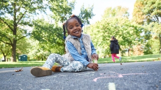 young girl outside at playground playing with chalk
