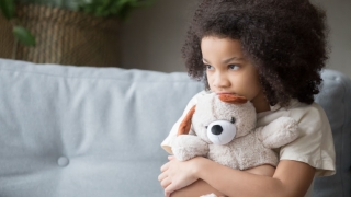 Scared young girl holding a stuffed animal