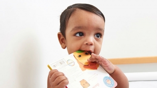 Toddler with book in his mouth