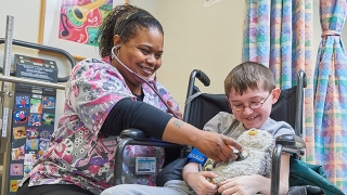 Boy in wheelchair, his stuffed animal is getting its vitals checked